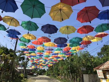 Low angle view of multi colored umbrellas hanging against sky