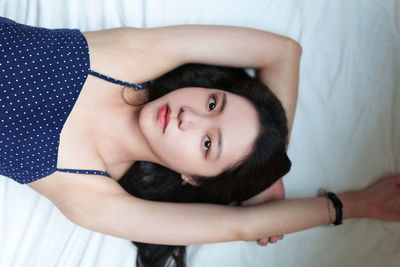 High angle portrait of young woman lying on bed