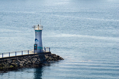 Lighthouse by sea against building