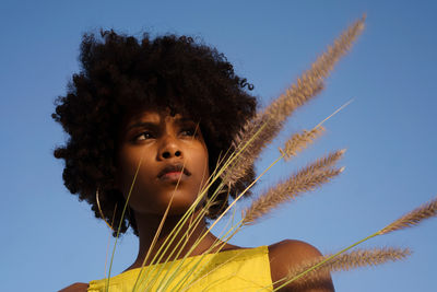 Portrait of a young black woman wearing yellow dress holding grass