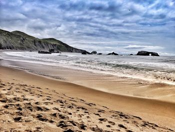 Scenic view of beach and waves against sky