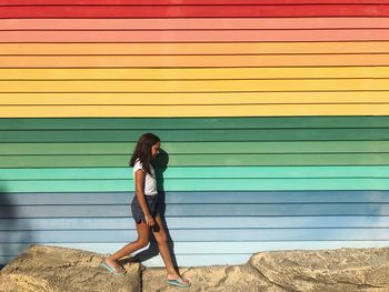 Side view of girl walking against metal in city