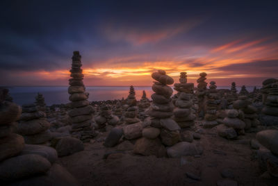 Stack of rocks on beach against sky during sunset