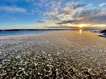 Surface level of beach against sky during sunset