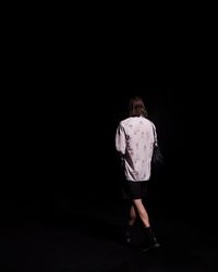 Rear view of woman standing against black background