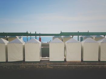 Deck chairs by sea against sky