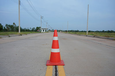 Road sign on street against sky