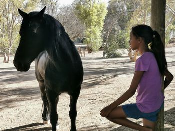 Full length of woman with horse in background