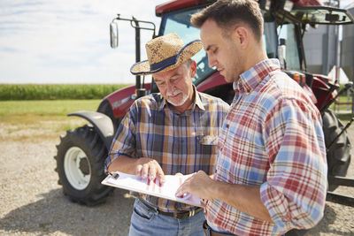 Two farmers looking at data from clipboard on the farm