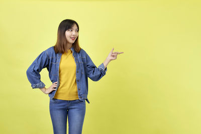 Portrait of smiling young woman against yellow background
