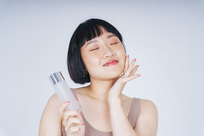 Portrait of beautiful woman holding hands against white background