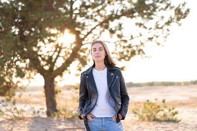 Portrait of woman standing against tree on field