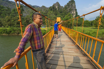 People standing on footbridge against trees