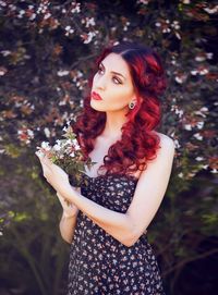 Portrait of beautiful young woman standing against plants