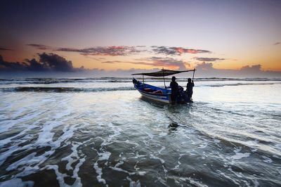 Scenic view of calm sea and boat at sunset