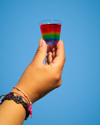 Midsection of woman holding drink against blue background