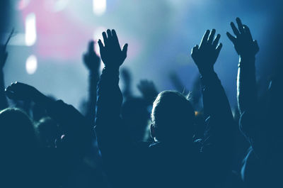 Rear view of crowd with arms outstretched at concert