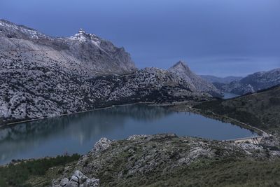 Scenic view of lake by mountains against sky