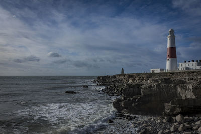 Lighthouse by sea against sky