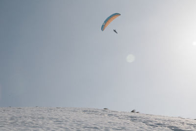 Person paragliding over sea against sky