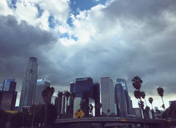 Low angle view of skyscrapers against cloudy sky