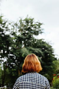 Rear view of woman against trees against sky