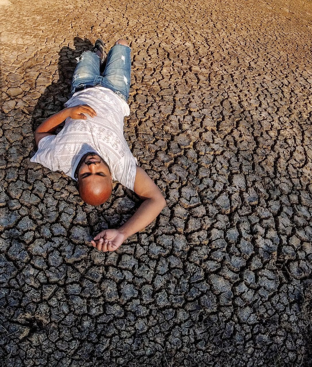 one person, lying down, full length, lifestyles, high angle view, real people, childhood, relaxation, child, leisure activity, day, casual clothing, men, nature, land, innocence, outdoors, girls, pebble