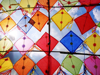 Low angle view of colorful decorative kites against cloudy sky