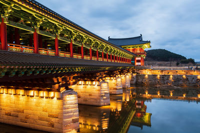 Illuminated bridge against cloudy sky