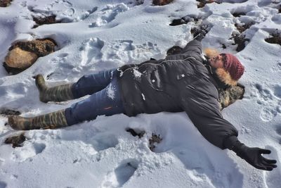 Man lying on snow covered field
