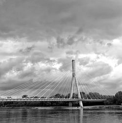 Bridge over river against cloudy sky