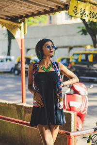 Woman in sunglasses standing at bus stop