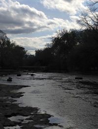 Scenic view of river against cloudy sky