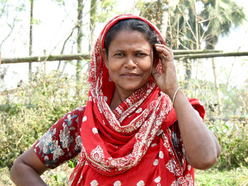 Portrait of young woman standing against trees