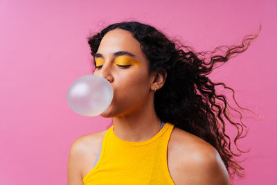 Close-up of young woman with balloons against pink background