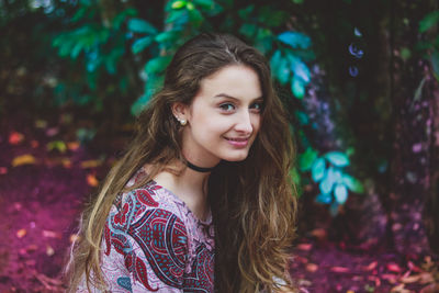 Portrait of smiling young woman standing against trees