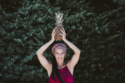 Portrait of a smiling young woman standing against trees