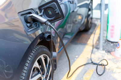 A cable is recharging an electric car at the charging station