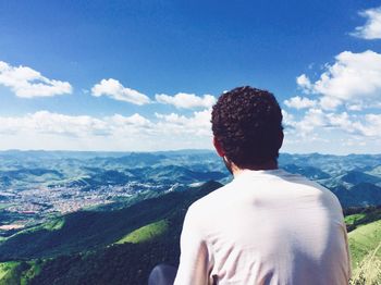 Rear view of man looking at mountains against sky