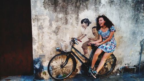 Portrait of smiling young woman sitting on bicycle