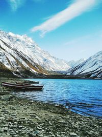 Scenic view of lake by snowcapped mountains against sky