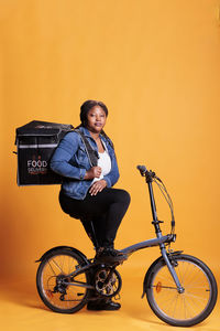 Man riding bicycle against orange background