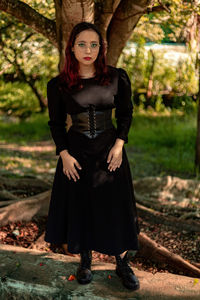 Portrait of young woman standing against trees