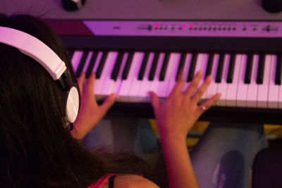 High angle view of woman with headphones playing piano