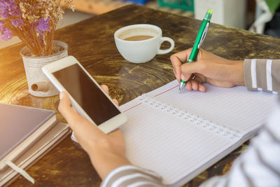 High angle view of woman holding coffee cup on table