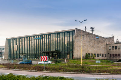 Road sign by building against sky in city