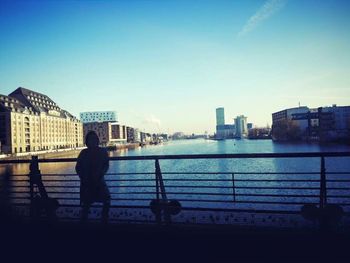 Rear view of woman standing by railing against sky