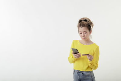Full length of a girl holding mobile phone against white background