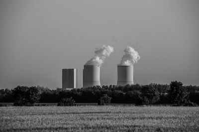 Smoke emitting from factory against sky