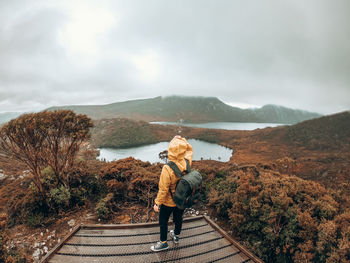 Rear view of woman standing on mountain against sky